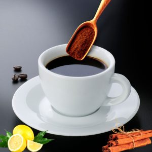 coffee and lemon juice in a cup with lemon cinnamon placed beside and some coffee in spoon shown over the glass