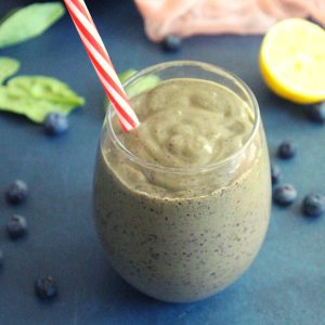 meal replacement smoothie in a glass with a straw to lose weight with avocado and berries placed beside as garnish